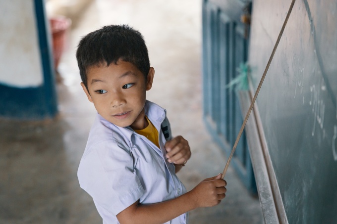 A first-grade student points to letters at the board as he sounds them out. When he gets stuck, he looks to the teacher for help. Somsanouk Primary School, Pak Ou District, Lao PDR. Credit: GPE/Kelley Lynch