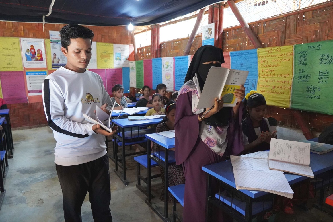 Teacher Mohammad Yunus helps one of his students with an assignment in Burmese. Credit: GPE/Salman Saeed